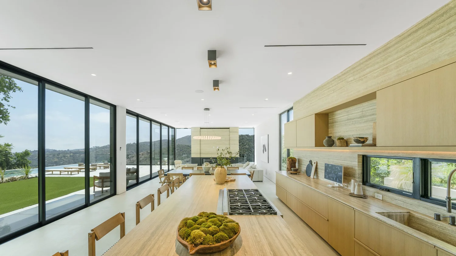 Bright modern kitchen and dining space with wide windows and hillside views.